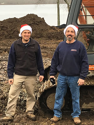 Scott and Todd Grenon have the holiday spirit as they sport Santa hats and represent Grenco Septic Systems and Excavation near their Hitachi backhoe.