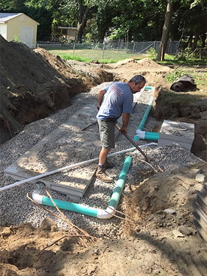 Septic system pipes and the distribution box get covered with some gravel and dirt as the excavation area gets finished.