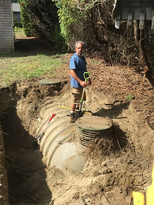 A Grenco Septic Systems and Excavation team member works hard ona job site showing an exposed septic pipe and lid.