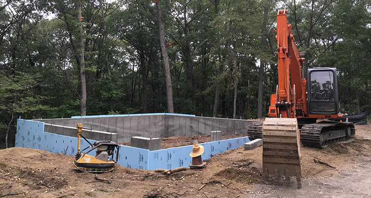 The forms for new foundations can be seen and Grenco's large Hitachi backhoe is on the job site as they install a new foundation at an excavated site.