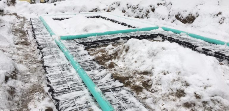 Snow covers pipes in an excavated leach field installed by Grenco