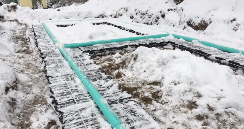Snow covers pipes in an excavated leach field installed by Grenco